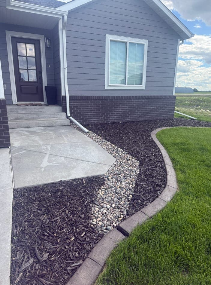 Stamped-concrete curb edging a river-rock and mulch walkway bed